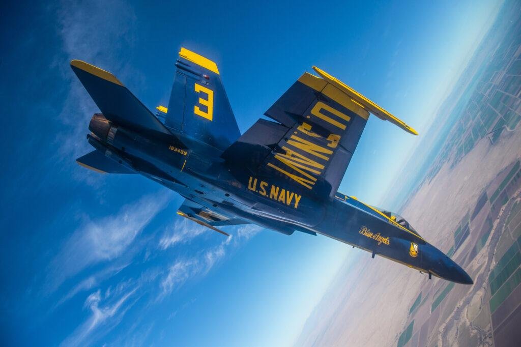 Blue Angel No. 3 Boeing F/A-18 Super Hornet performs a high-speed banking maneuver during a flight demonstration.