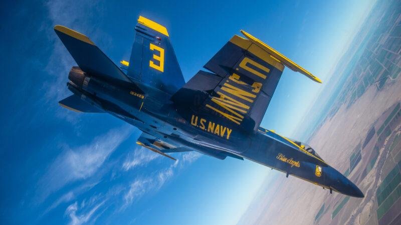 Blue Angel No. 3 Boeing F/A-18 Super Hornet performs a high-speed banking maneuver during a flight demonstration.