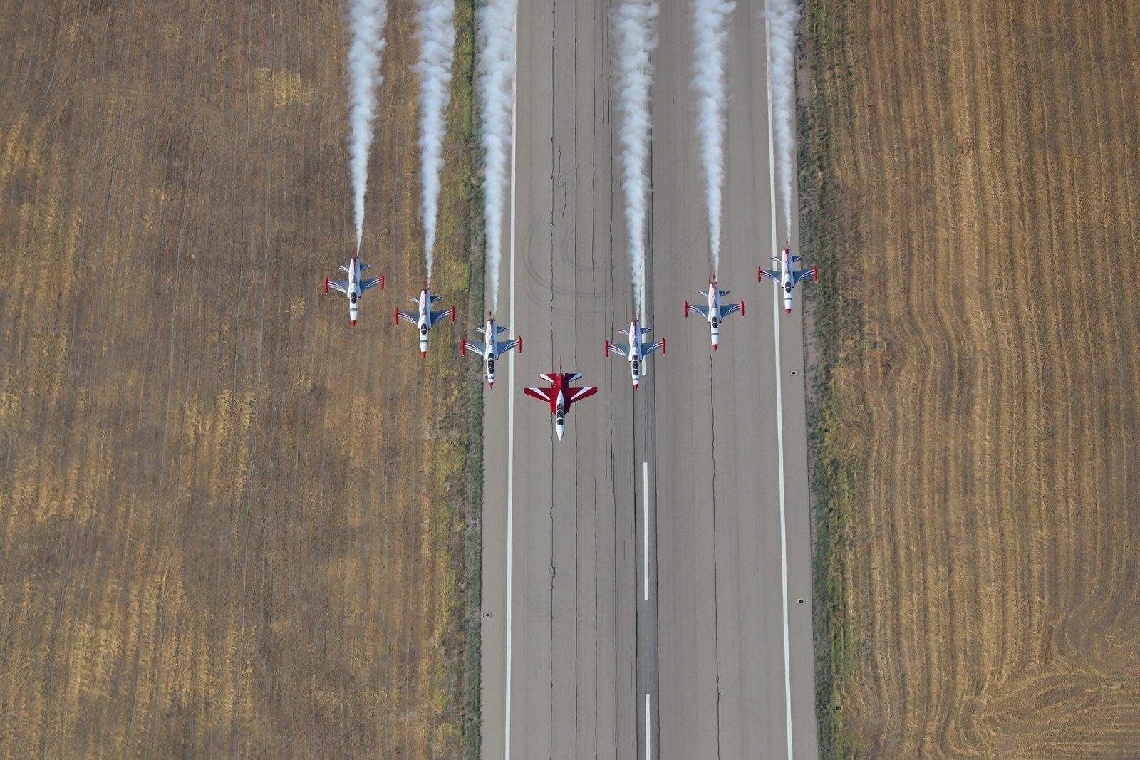 HÜRJET flying in formation with Turkish Stars NF-5 aircraft over a runway