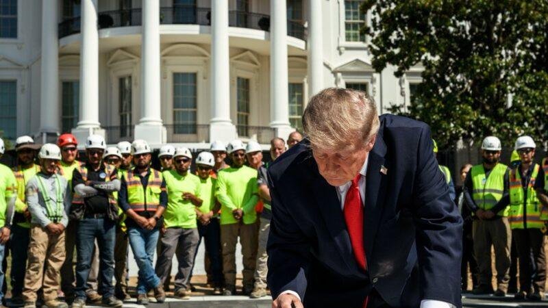 President Donald Trump signs a granite section of the new White House South Lawn helipad in August 2026