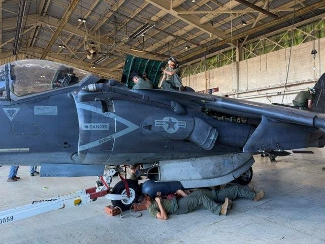 Marine Corps maintainers work beneath the last USMC-built AV-8B Harrier II during demilitarization at MCAS Cherry Point