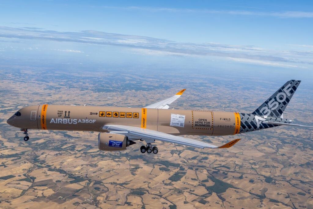 Airbus A350F freighter F-WXLD in flight over farmland, in a parcel-themed livery with cargo labels and an orange A350F tail band
