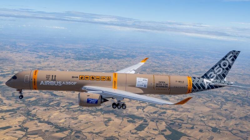 Airbus A350F freighter F-WXLD in flight over farmland, in a parcel-themed livery with cargo labels and an orange A350F tail band