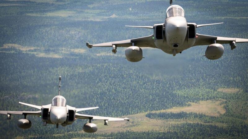 Gripen engine cooperation illustrated by two Saab JAS 39 Gripen fighter jets flying in formation above a forested landscape.