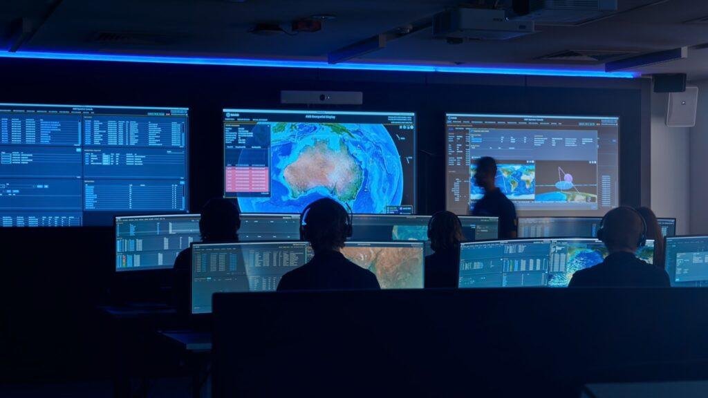 Saab Allied Mission System operations room with personnel monitoring space surveillance dashboards and geospatial displays.