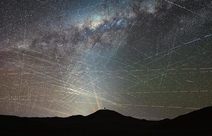 ESA satellite interference illustrated by numerous satellite trails crossing the night sky above astronomical observatories in Chile's Atacama Desert.