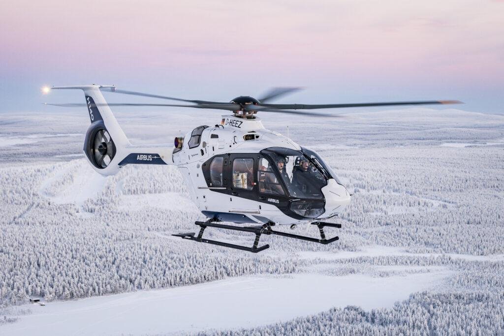 Airbus H140 tests during a cold-weather flight campaign, showing the helicopter flying over snow-covered forests.