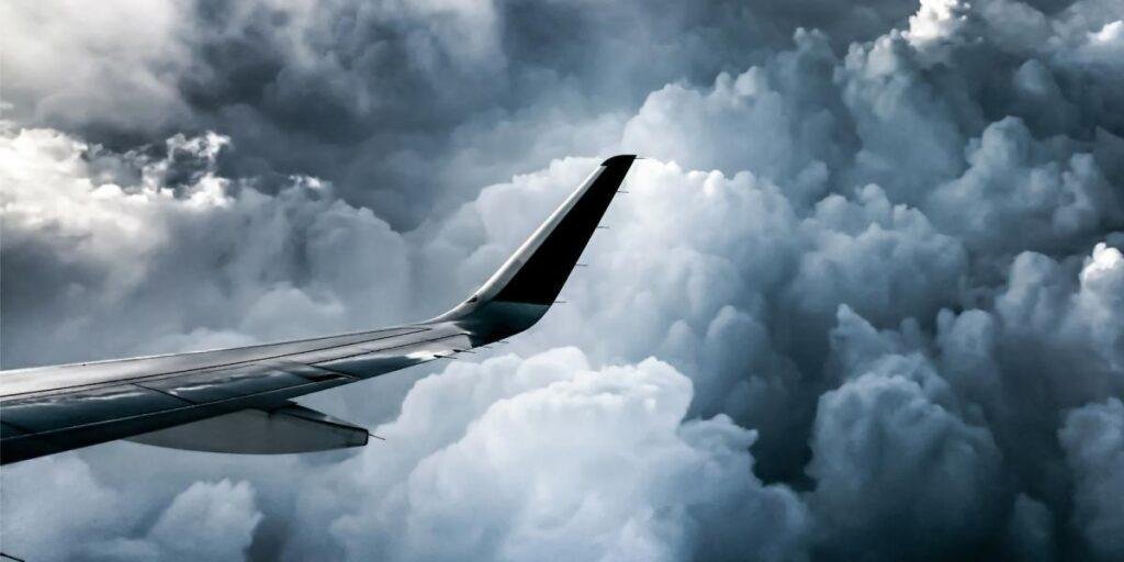Airplane wing seen against dramatic storm clouds during flight