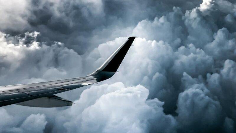 Airplane wing seen against dramatic storm clouds during flight
