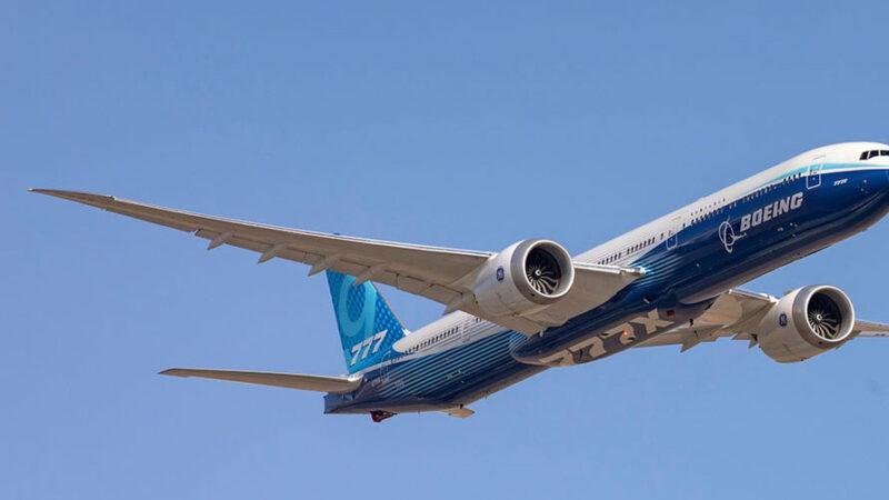 Boeing Hutchinson Partnership illustrated by a Boeing 777X widebody aircraft flying against a clear blue sky in Boeing's blue test-aircraft livery.