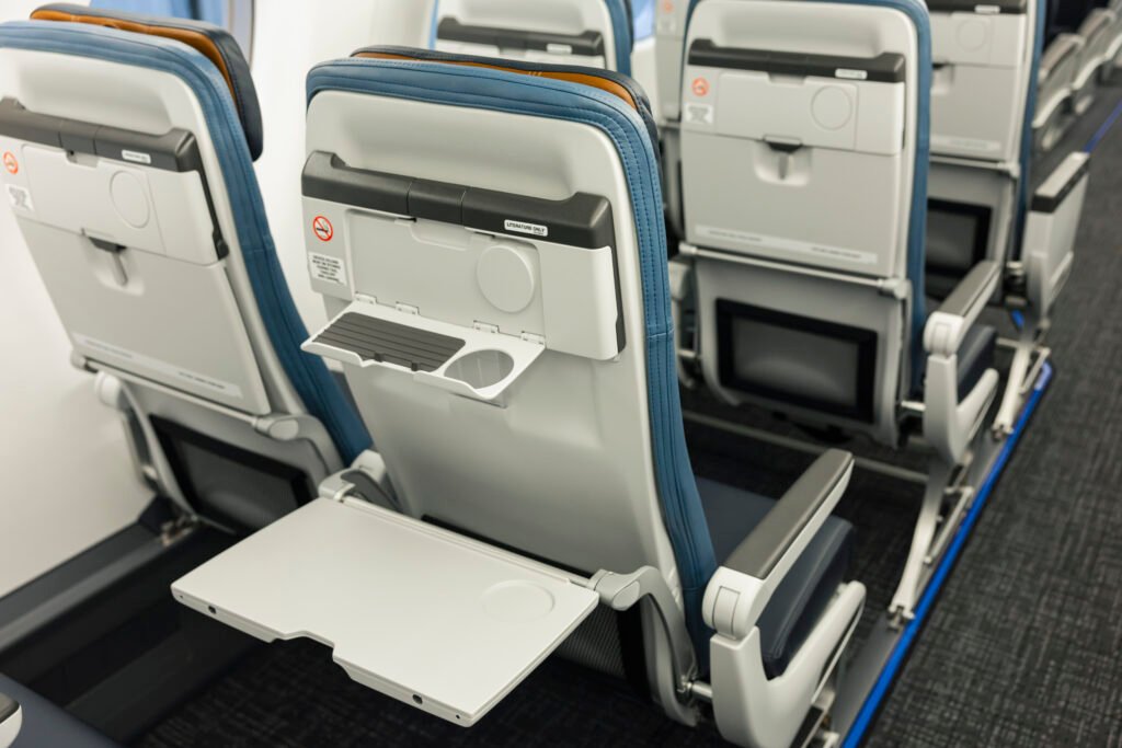 Embraer E175 Seats showing the rear of the new RECARO seats with tray tables and cup holders in the American Eagle cabin.