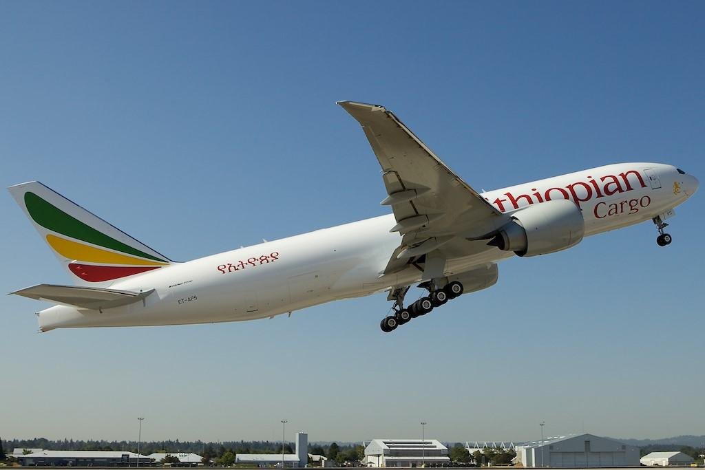Ethiopian Airlines cargo Boeing 777 freighter, registration ET-APS, taking off with its landing gear extended against a clear blue sky.
