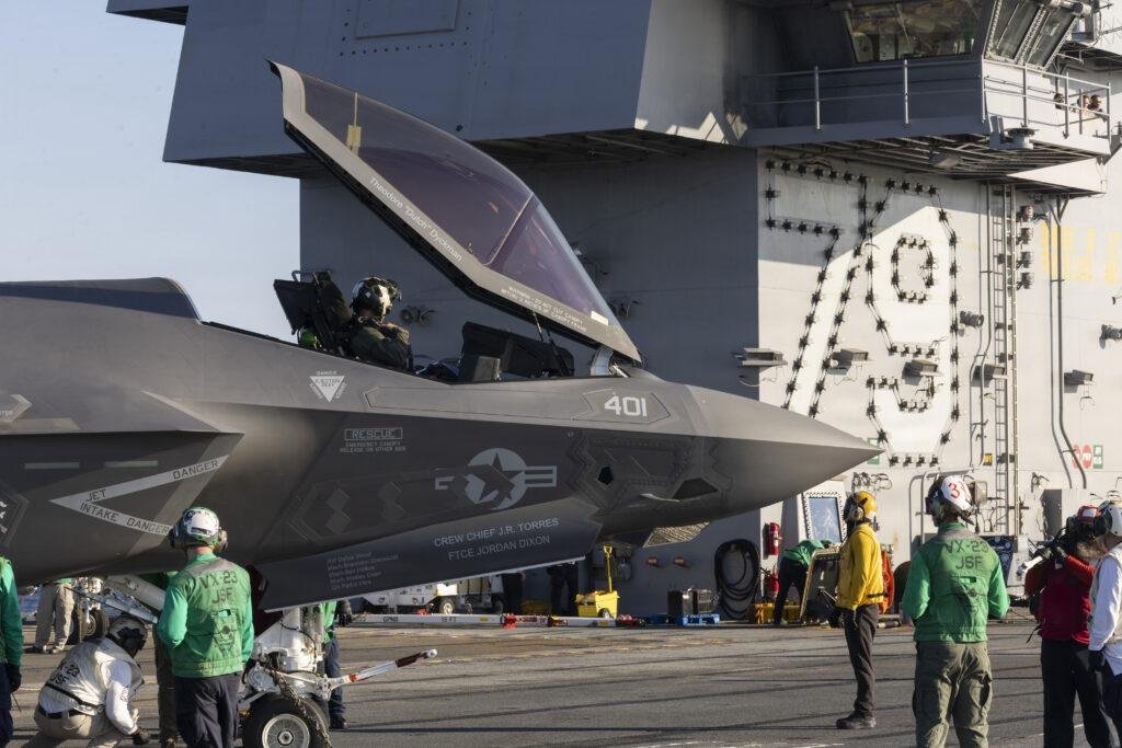 U.S. Navy F-35C Lightning II fighter with its canopy open as flight deck personnel prepare the aircraft for carrier operations.