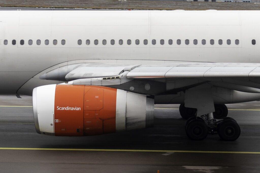 A Rolls-Royce Trent 700 engine with orange cowlings under the wing of an SAS Scandinavian Airlines Airbus A330