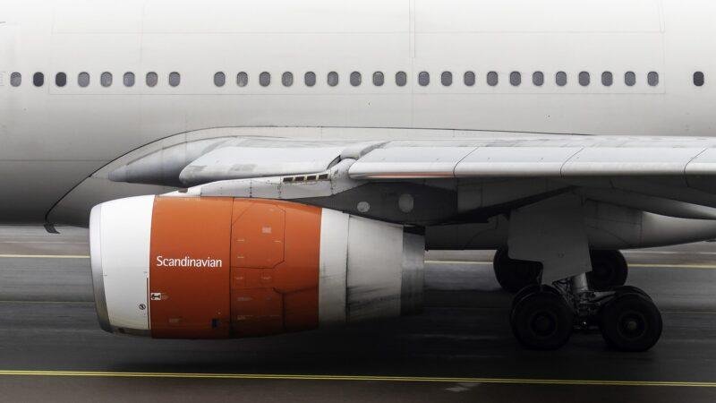 A Rolls-Royce Trent 700 engine with orange cowlings under the wing of an SAS Scandinavian Airlines Airbus A330