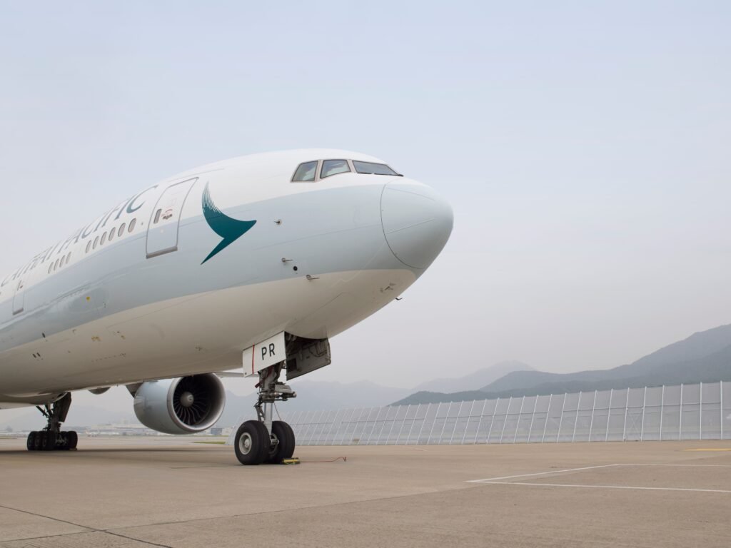 HAECO Cathay Boeing 777 landing gear support illustrated by a Cathay Pacific widebody aircraft parked on an airport apron with its nose landing gear visible.
