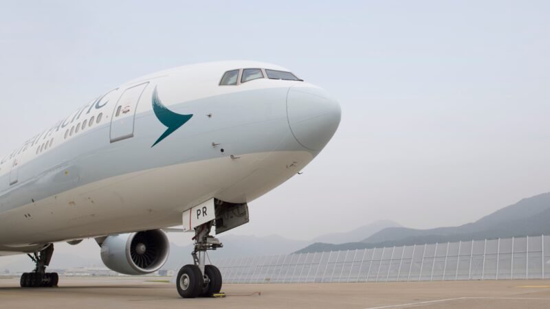 HAECO Cathay Boeing 777 landing gear support illustrated by a Cathay Pacific widebody aircraft parked on an airport apron with its nose landing gear visible.