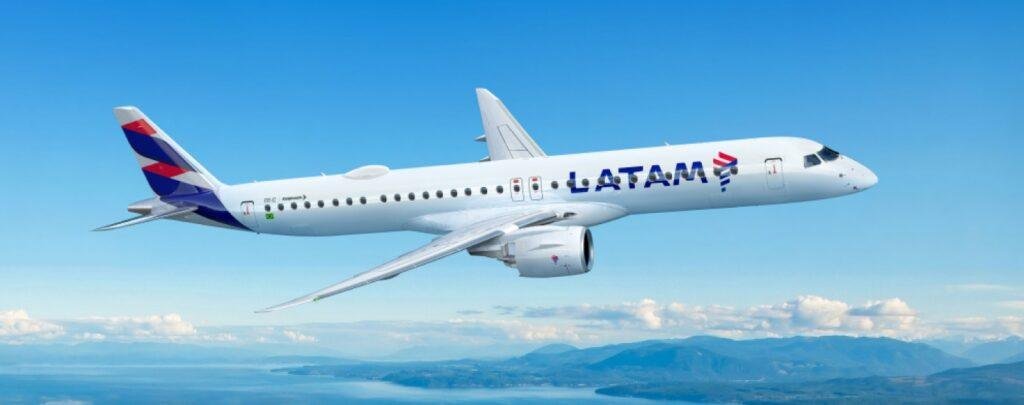 LATAM E195-E2 Embraer passenger jet illustrated in LATAM Airlines livery flying above a coastal landscape with mountains and blue skies.