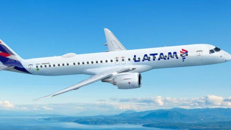 LATAM E195-E2 Embraer passenger jet illustrated in LATAM Airlines livery flying above a coastal landscape with mountains and blue skies.