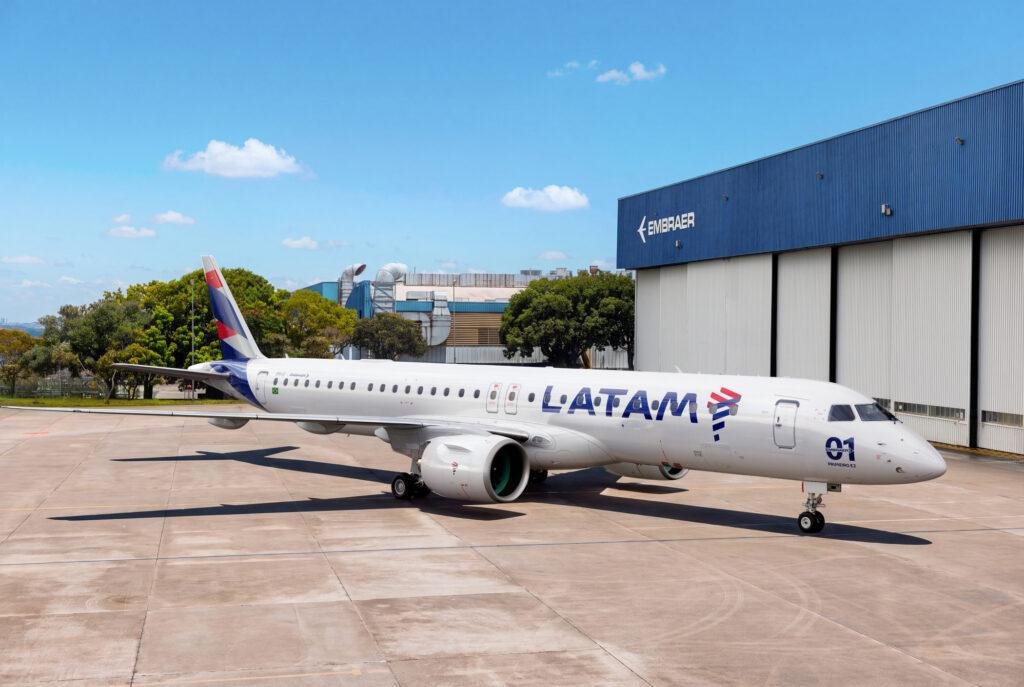 LATAM Embraer delivery — E195-E2 passenger aircraft in LATAM Airlines livery parked outside an Embraer manufacturing hangar.