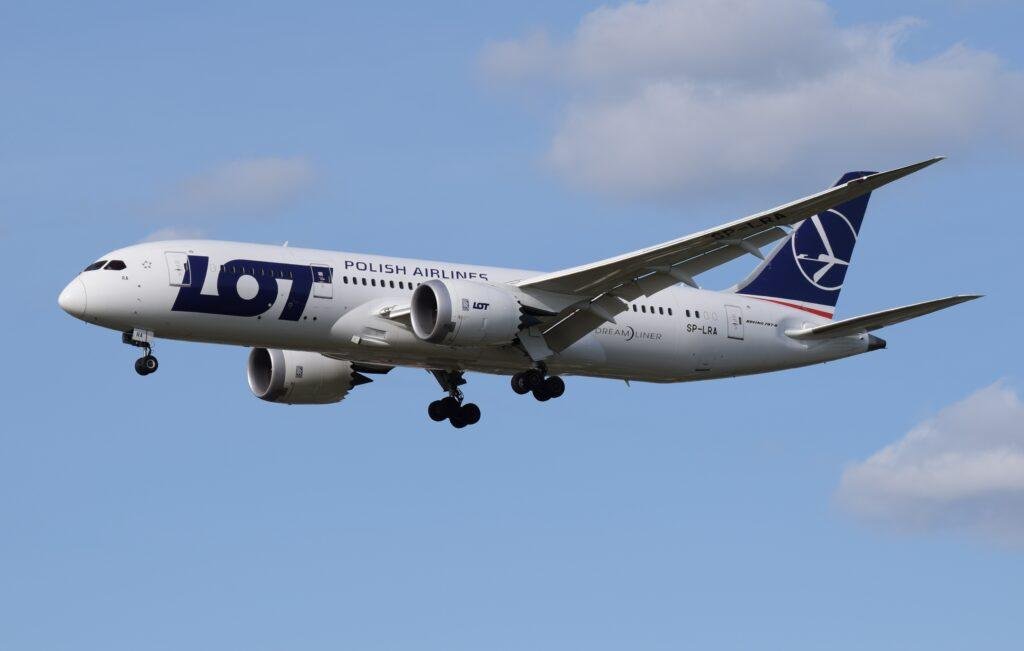 LOT Warsaw Bangkok flights illustrated by a LOT Polish Airlines Boeing 787-8 Dreamliner SP-LRA approaching landing with its landing gear extended.