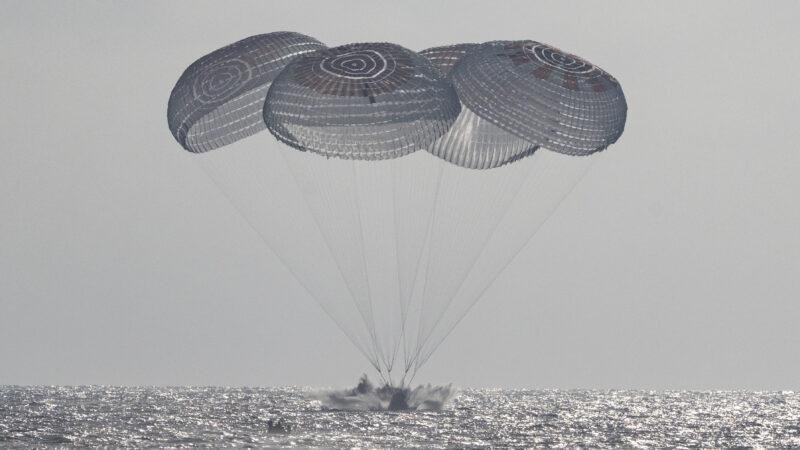 NASA Crew-12 return showing the SpaceX Crew Dragon Freedom spacecraft splashing down beneath parachutes in the Pacific Ocean off California.