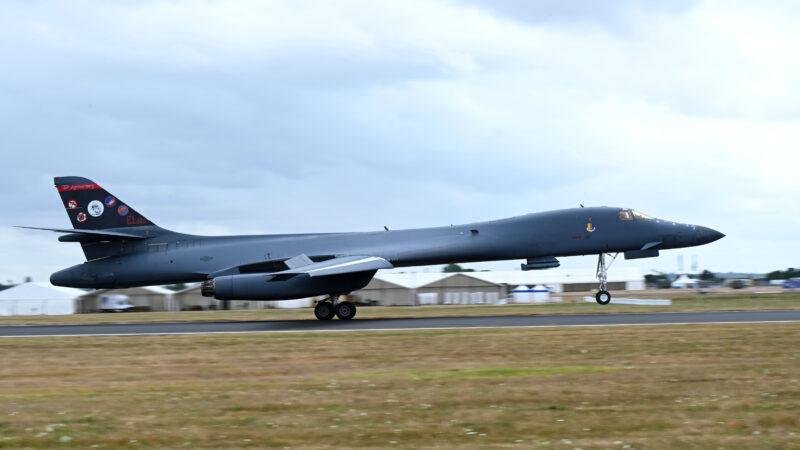 B-1B Lancer touching down on a runway under a grey sky, with 80th anniversary tail art