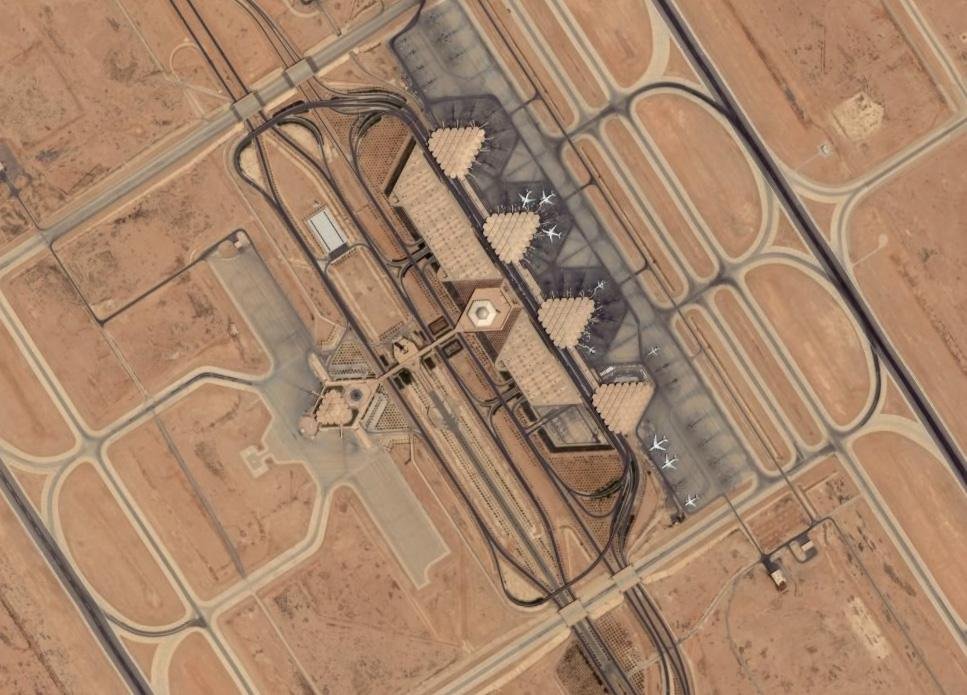 Riyadh flight cancellations illustrated by an aerial satellite view of airport terminals, parked aircraft, taxiways, and surrounding aviation infrastructure.