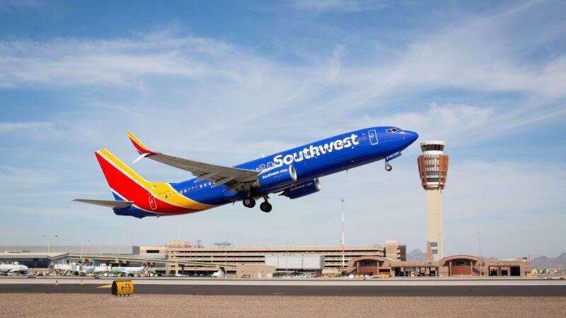 Southwest Airlines Boeing 737 taking off near an airport control tower, illustrating Southwest Rapid Rewards 2027 loyalty program changes.