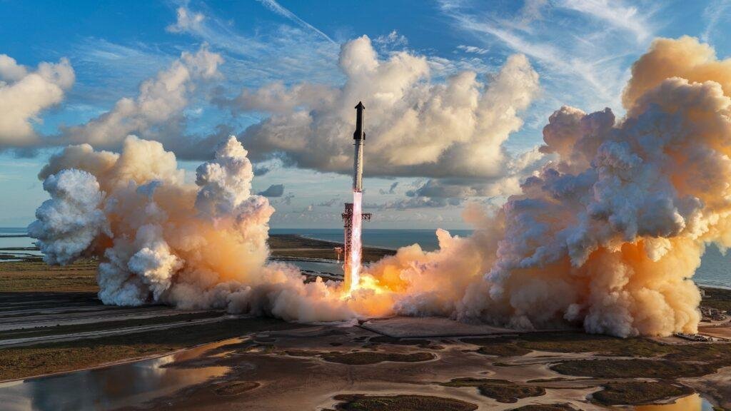 Aerial view of Starship Flight 14 lifting off from Starbase, Texas, with large orange and white clouds on either side