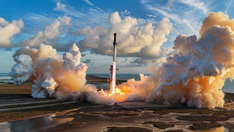 Aerial view of Starship Flight 14 lifting off from Starbase, Texas, with large orange and white clouds on either side
